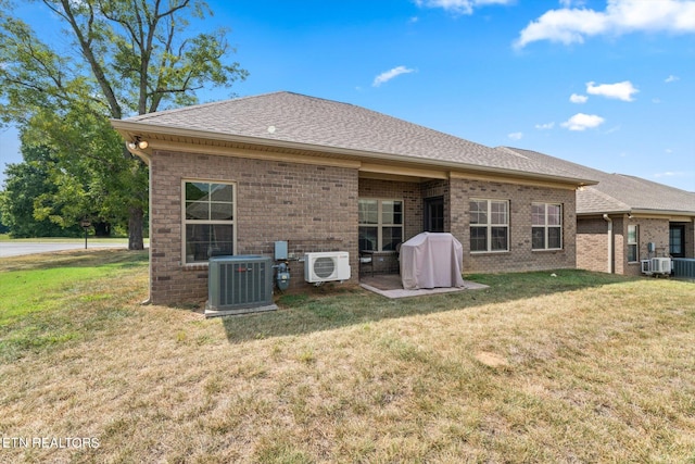 rear view of house with roof with shingles, brick siding, central AC, and a yard