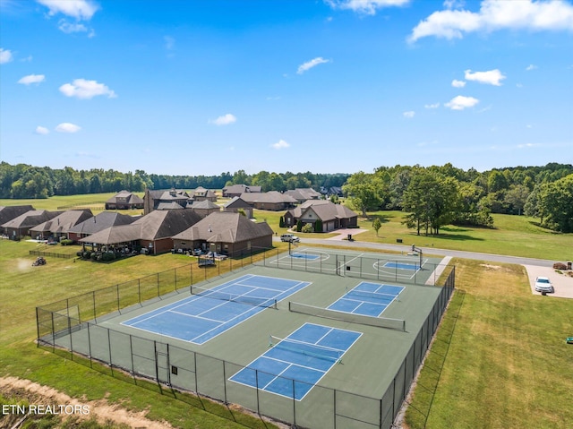 view of tennis court with a lawn, fence, and a residential view