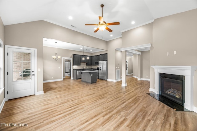 living area featuring light wood finished floors, ceiling fan with notable chandelier, visible vents, and baseboards