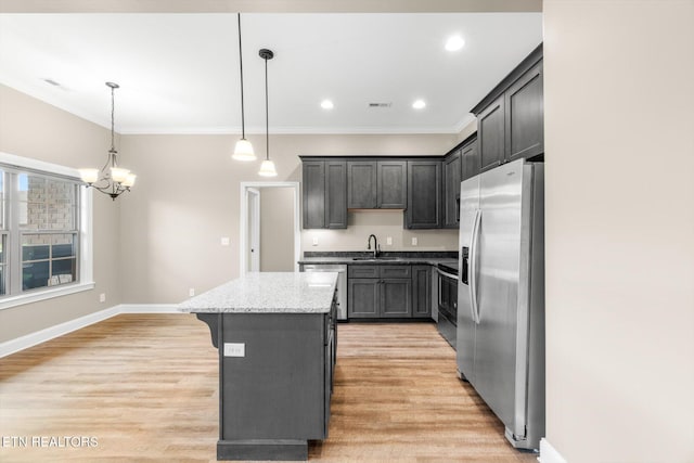 kitchen featuring a sink, a kitchen island, a chandelier, light wood-style flooring, and stainless steel appliances