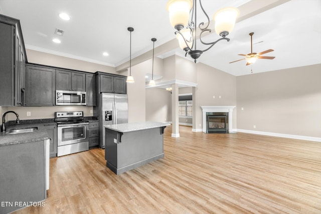 kitchen featuring stainless steel appliances, a kitchen island, a sink, light wood-style floors, and a ceiling fan