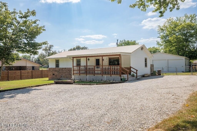 ranch-style house with covered porch, a front yard, a garage, and an outdoor structure