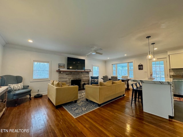 living room with dark wood-type flooring, crown molding, a fireplace, and ceiling fan