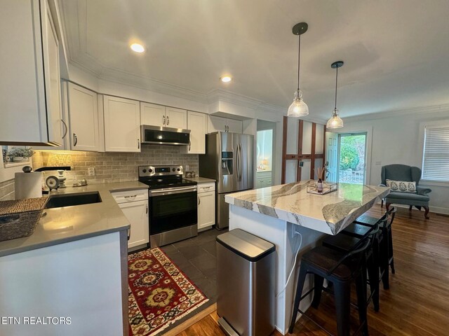 kitchen featuring extractor fan, dark wood-type flooring, pendant lighting, white cabinetry, and appliances with stainless steel finishes