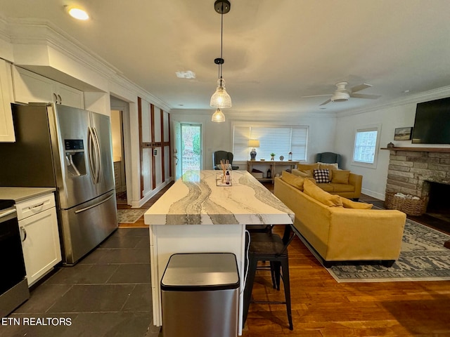 kitchen with white cabinets, dark hardwood / wood-style flooring, ornamental molding, pendant lighting, and a center island