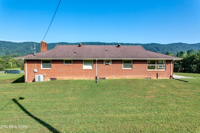 rear view of house featuring a mountain view, a yard, and central AC