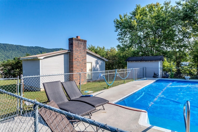 view of swimming pool featuring a mountain view, a yard, a patio, and a shed