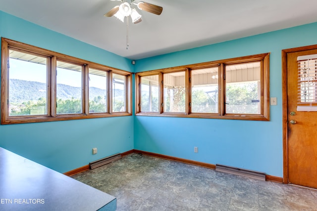 interior space with a baseboard heating unit, ceiling fan, and a mountain view