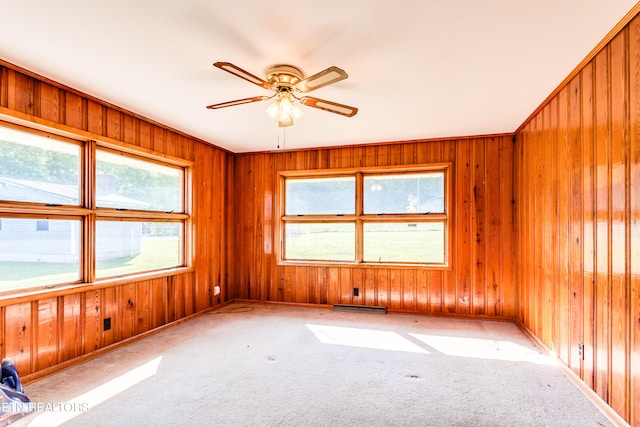 spare room with light colored carpet, ceiling fan, and wood walls