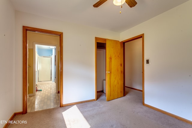 unfurnished bedroom with a closet, light colored carpet, connected bathroom, and ceiling fan