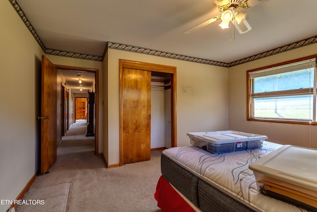 carpeted bedroom featuring ceiling fan and a closet