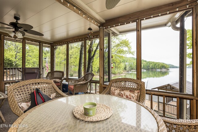 sunroom / solarium with a healthy amount of sunlight, ceiling fan, beam ceiling, and a water view