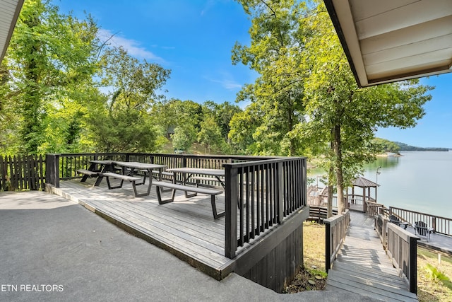 wooden terrace with outdoor dining space and a water view