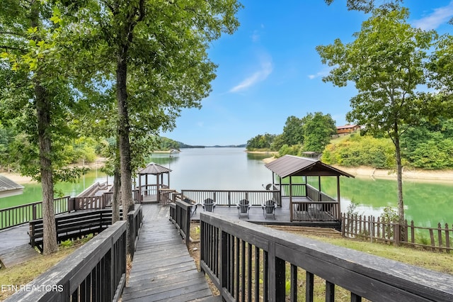view of dock with a water view, a gazebo, and fence