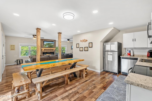 kitchen with a fireplace, a ceiling fan, wood finished floors, and stainless steel appliances