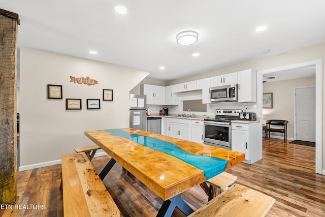 kitchen featuring light countertops, wood finished floors, stainless steel appliances, and tasteful backsplash