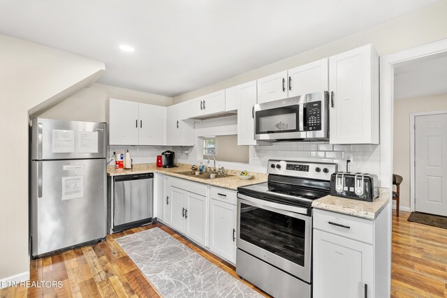 kitchen featuring light wood-type flooring, appliances with stainless steel finishes, white cabinetry, and sink