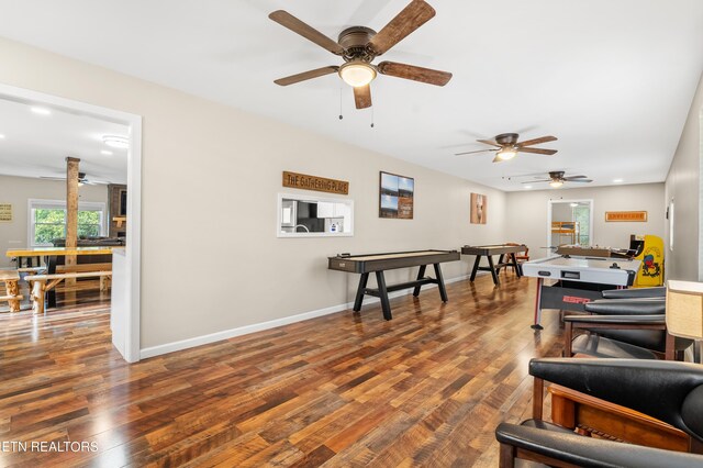 living room with dark wood-type flooring, ceiling fan, and a wealth of natural light