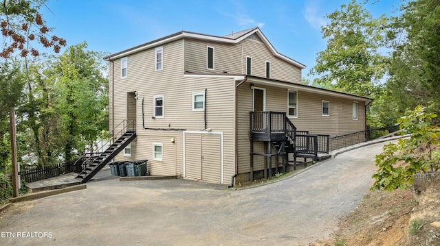 back of house featuring driveway, stairs, and fence