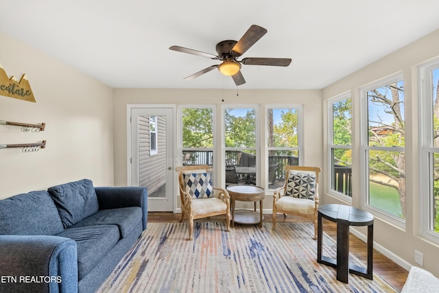 sunroom / solarium featuring baseboards, wood finished floors, and a deck