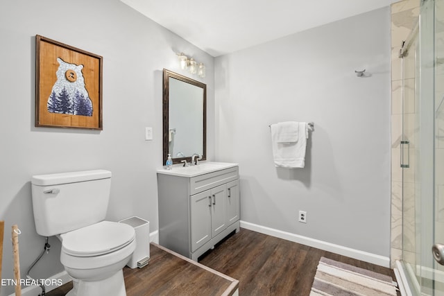 full bath with toilet, vanity, a shower stall, wood finished floors, and baseboards