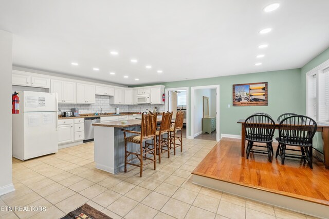 kitchen with white appliances, white cabinetry, and a breakfast bar