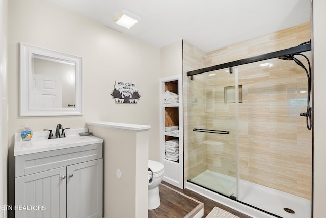 bathroom with toilet, vanity, a stall shower, and wood finished floors