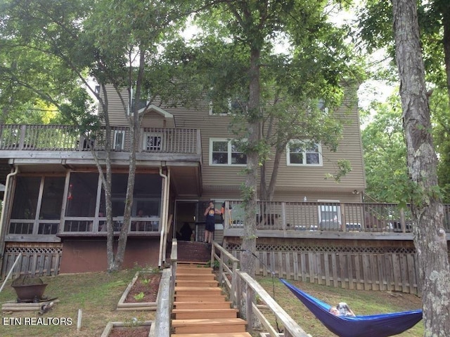 rear view of property with a sunroom and stairway