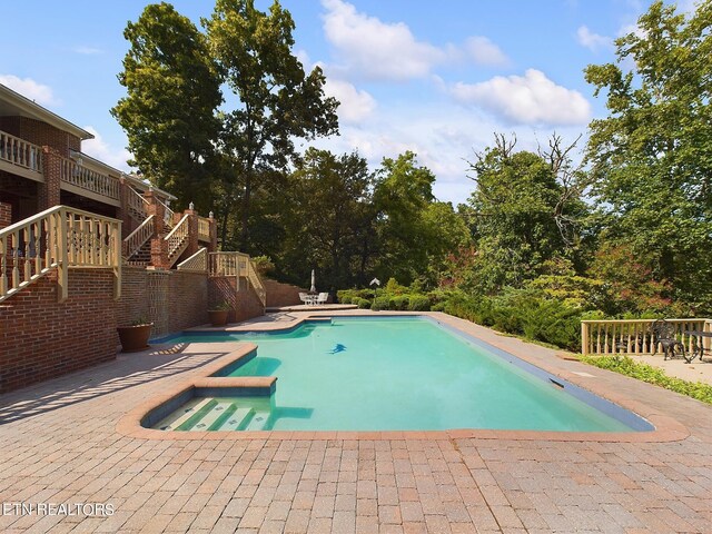 view of swimming pool featuring a patio, a deck, and a jacuzzi