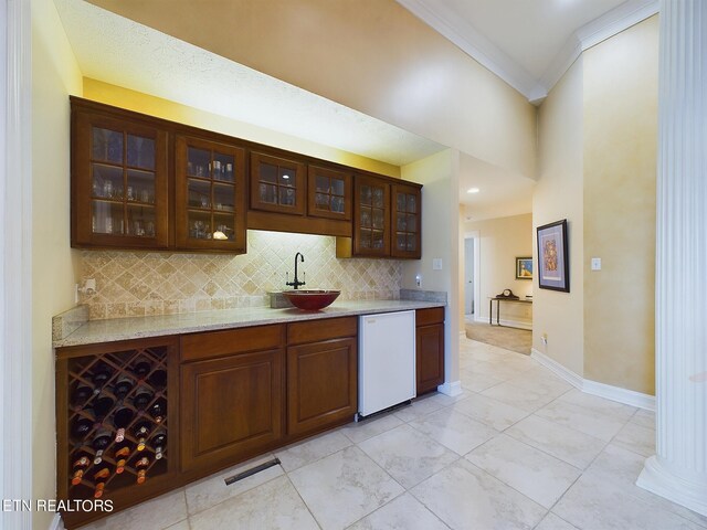 bar featuring sink, backsplash, dark brown cabinetry, and dishwasher