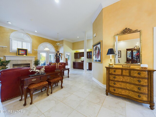 miscellaneous room featuring light tile patterned floors, ceiling fan, ornamental molding, a tile fireplace, and french doors