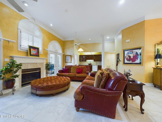 living room featuring a tiled fireplace, crown molding, and light tile patterned floors