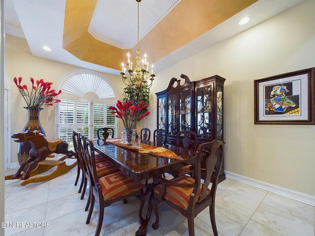 tiled dining room featuring crown molding, a raised ceiling, and an inviting chandelier