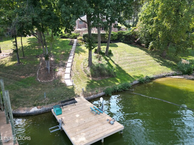 view of dock with a water view and a yard