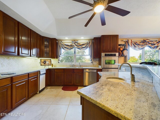 kitchen with appliances with stainless steel finishes, light stone countertops, sink, and light tile patterned floors