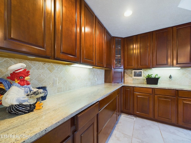 155 Lake Crest Dr, Lenoir City, TN 37772 - kitchen featuring a textured ceiling, glass insert cabinets, light stone countertops, and backsplash