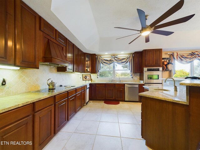 kitchen featuring light stone counters, stainless steel appliances, a wealth of natural light, and custom exhaust hood