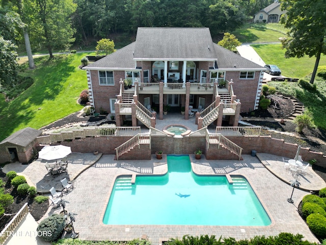 rear view of property featuring a patio, a pool with hot tub, and a yard