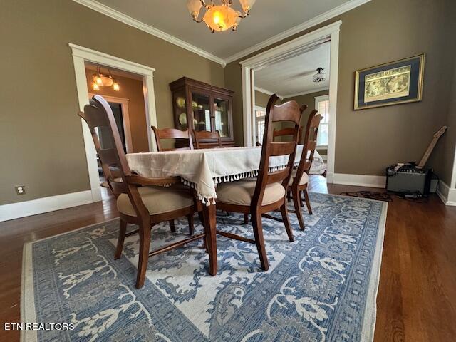 dining room with dark wood-type flooring, a notable chandelier, and ornamental molding