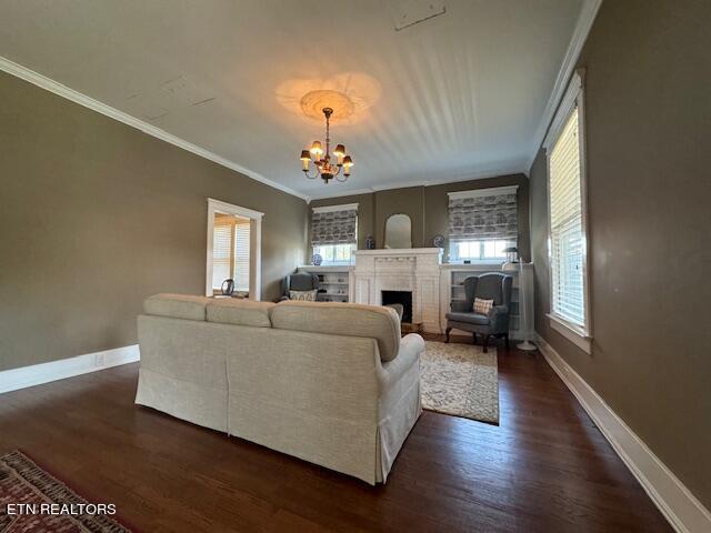 living room with crown molding, dark hardwood / wood-style floors, and an inviting chandelier