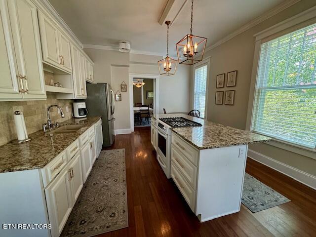 kitchen with stainless steel appliances, white cabinetry, hanging light fixtures, and sink