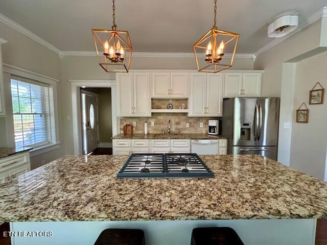 kitchen featuring pendant lighting, stainless steel appliances, white cabinetry, and crown molding