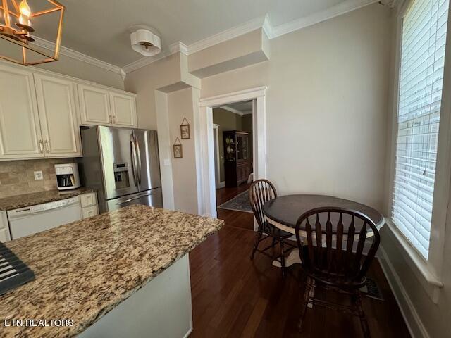 kitchen with stainless steel refrigerator with ice dispenser, a healthy amount of sunlight, and light stone countertops