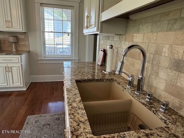 details with decorative backsplash, dark hardwood / wood-style flooring, light stone countertops, and sink