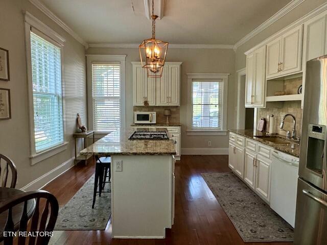 kitchen with a healthy amount of sunlight, pendant lighting, a kitchen island, and stainless steel appliances