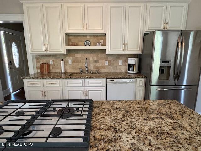 kitchen featuring stainless steel fridge with ice dispenser, white dishwasher, white cabinetry, and dark stone countertops