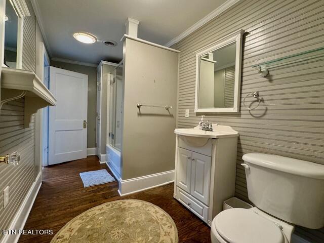 full bathroom with crown molding, hardwood / wood-style floors, toilet, shower / bath combination with glass door, and vanity