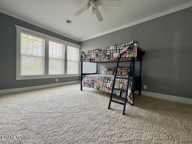 carpeted bedroom featuring ceiling fan and crown molding