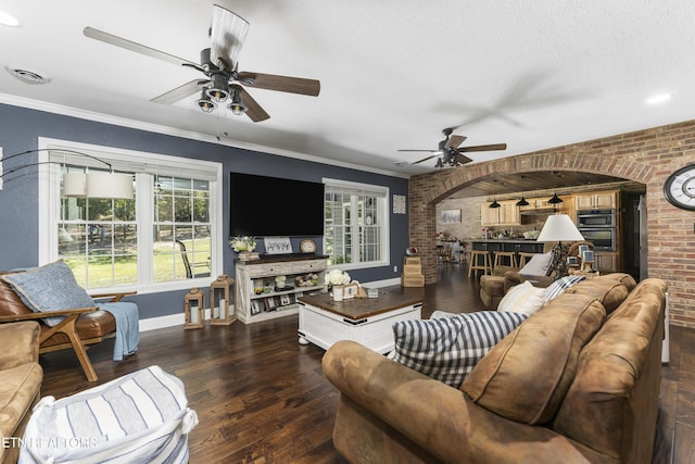 living room featuring dark hardwood / wood-style flooring, brick wall, a textured ceiling, ceiling fan, and crown molding