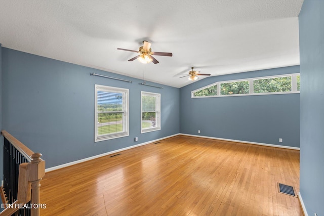 spare room with lofted ceiling, a wealth of natural light, wood-type flooring, and ceiling fan